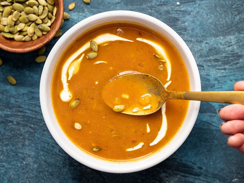 This flavorful and easy pumpkin soup takes less than 30 minutes to make and is the perfect simple side for a gooey grilled cheese sandwich! BudgetBytes.com One bowl of easy tomato soup with sour cream swirled in and a gold spoon in the middle