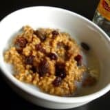 Bowl of gingerbread oatmeal topped with dried cranberries.
