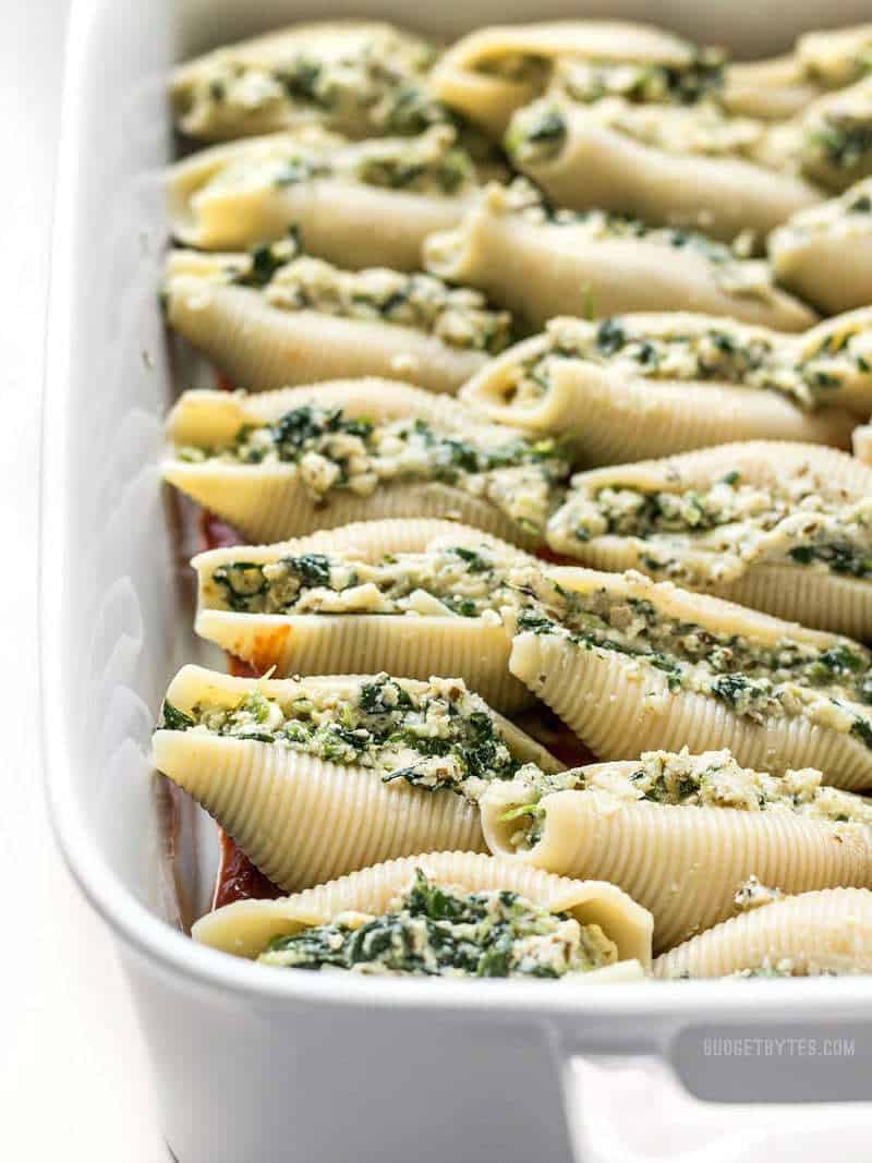 These easy Pesto Stuffed Shells are stuffed with two cheeses, pesto, and spinach. Perfect for meal prep or freezing portions for later! Close up of unbaked Pesto Stuffed Shells without sauce.