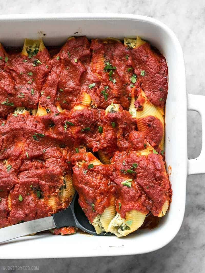 These easy Pesto Stuffed Shells are stuffed with two cheeses, pesto, and spinach. Perfect for meal prep or freezing portions for later! Side shot of baked Pesto Stuffed Shells.