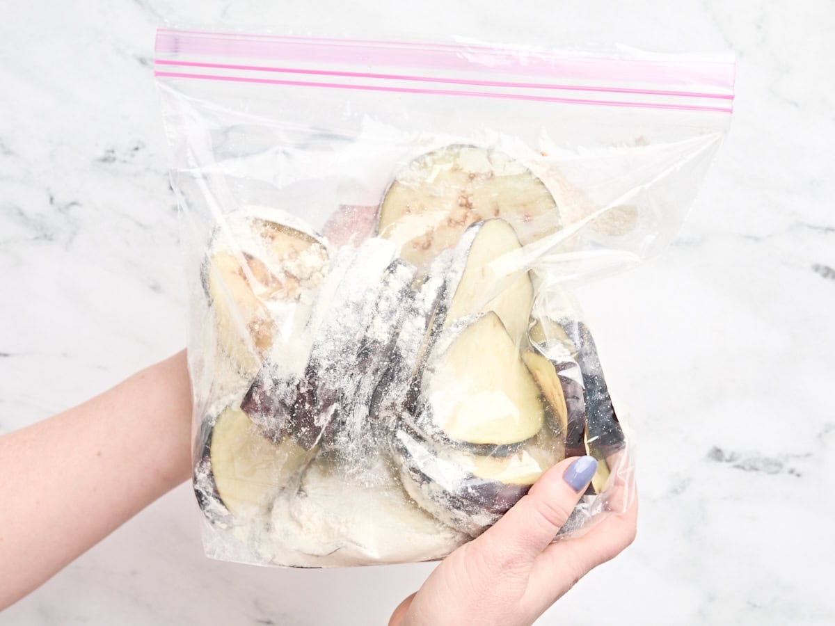 Eggplant slices in a ziplock bag of flour.