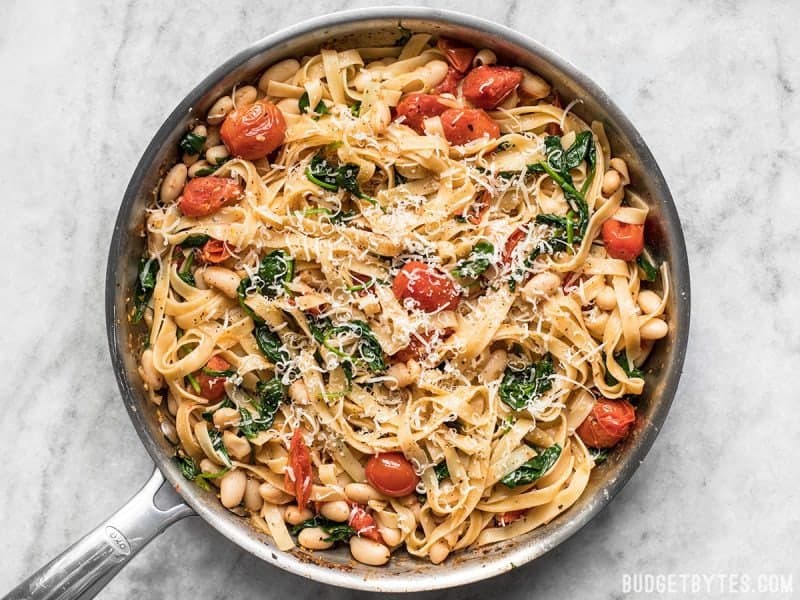 This Tuscan White Bean Pasta is a fast and flavorful dish that is perfect for weeknight dinners. Caramelized garlic, basil, and Parmesan add BIG flavor! Budetbytes.com Pasta topped with freshly grated Parmesan