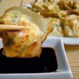 Lobster and cream cheese wontons dipped in soy sauce with chopsticks.
