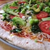 Raw pizza topped with fresh vegetables.