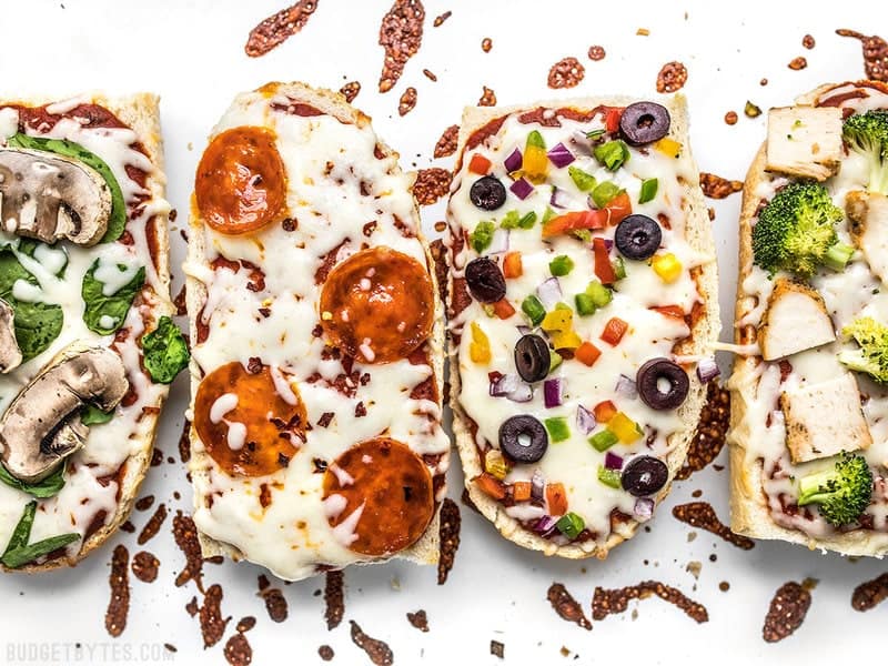 French Bread Pizza is the perfect budget-friendly fast and easy weeknight dinner. Customize the toppings to fit your taste buds or what you have on hand! Budgetbytes.com Close up of four French Bread Pizzas on a baking sheet