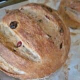Baked cranberry walnut bread presented on baking sheet.