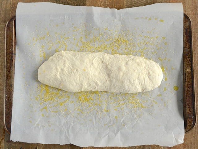 Baking sheet lined with parchment paper with shaped Ciabatta Dough placed on top ready to cook