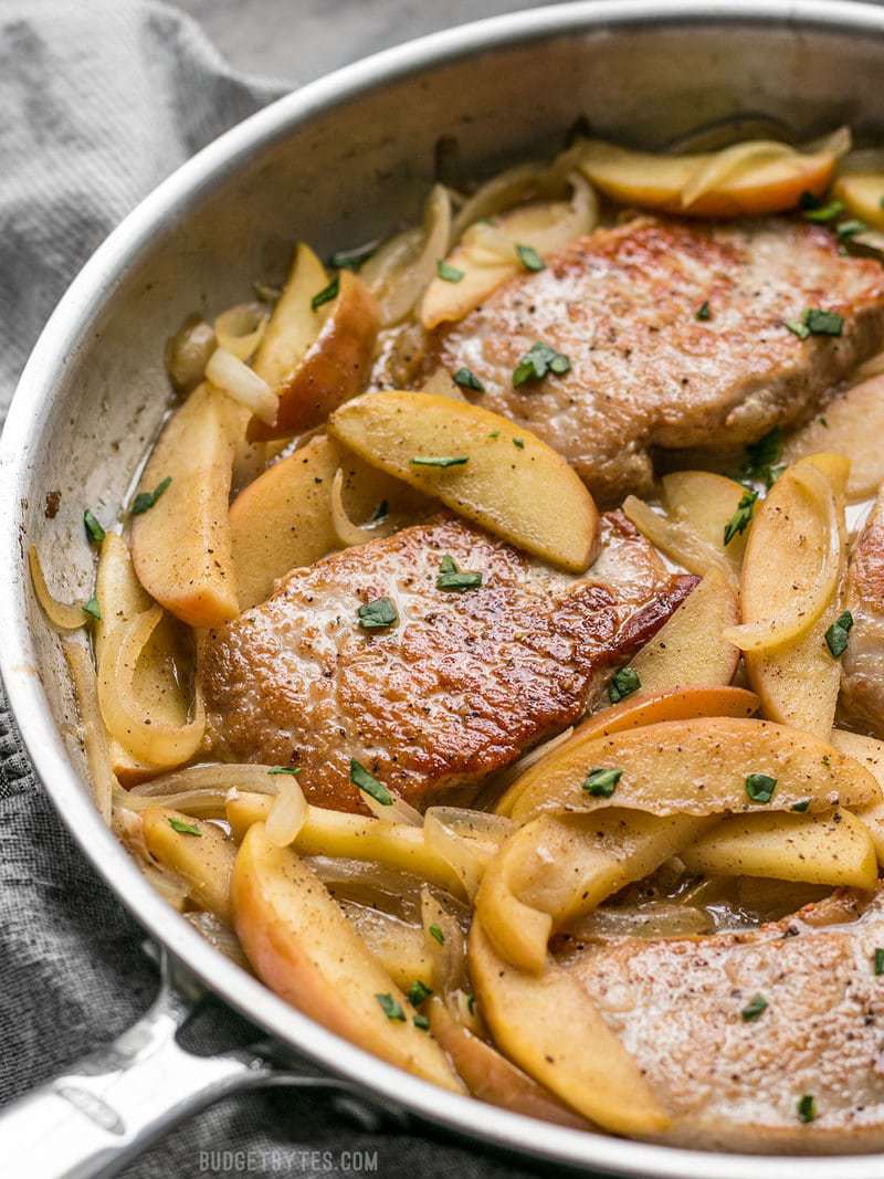 These Apple Spice Pork Chops are smothered with apples, onions, cinnamon, and a buttery pan sauce that is sweet, salty, and rich. Budgetbytes.com Close side view of Apple Spice Pork Chops in the skillet