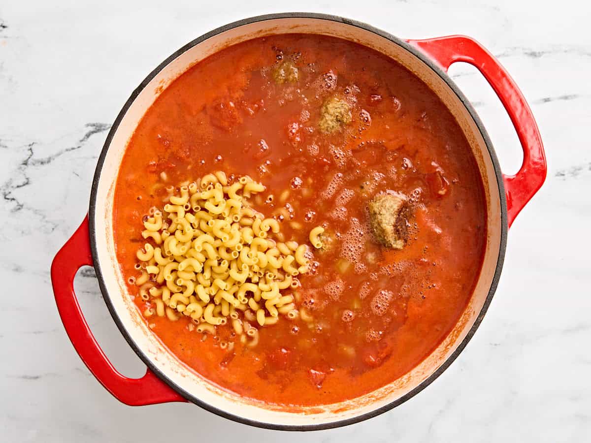 Dried pasta and cooked turkey meatballs added to a pot of meatball soup.
