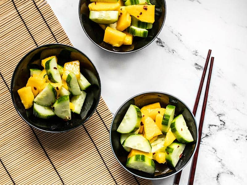 Fresh cucumber and tropical mango come together with a sweet and spicy dressing to make this light and refreshing Cucumber Mango Salad. Budgetbytes.com Three bowls of cucumber mango salad on a bamboo mat with chopsticks.