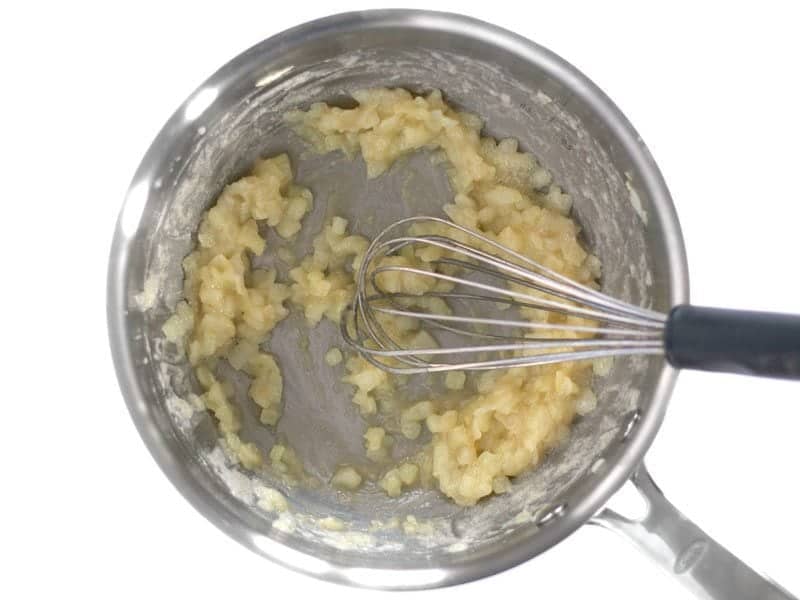 Flour added to onion and butter to create roux, mixed with whisk