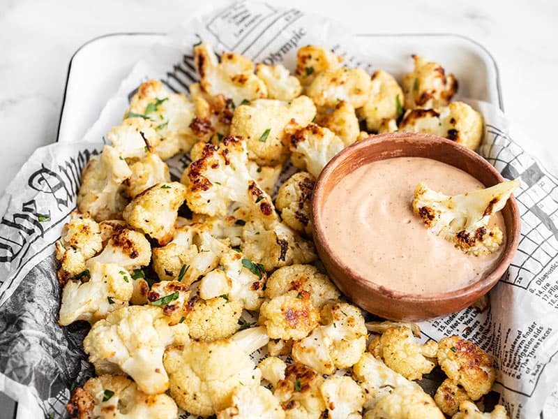 Garlic parmesan roasted cauliflower is an easy, flavorful side dish or snack that will have everyone begging for seconds. Budgetbytes.com Side view of a tray full of Garlic Parmesan Roasted Cauliflower
