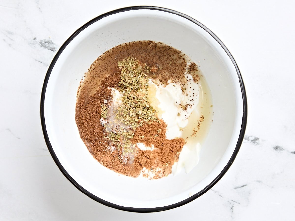 The ingredients to make a marinade for chicken shawarma in a mixing bowl.