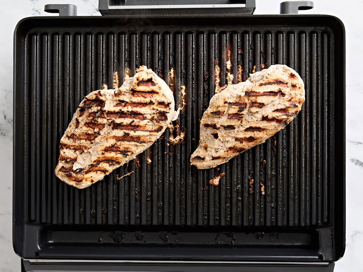 Cooked marinaded chicken breasts on a grill.