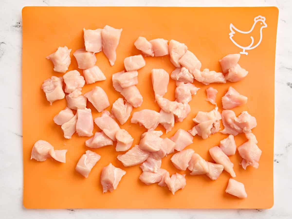 Diced chicken breast on a meat preparation mat.