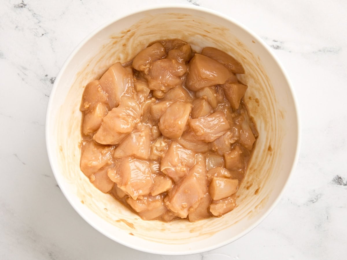 Diced chicken breast covered in a homemade marinade in a bowl.