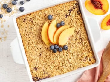 Overhead view of a baking dish of baked oatmeal topped with peach slices and blueberries.