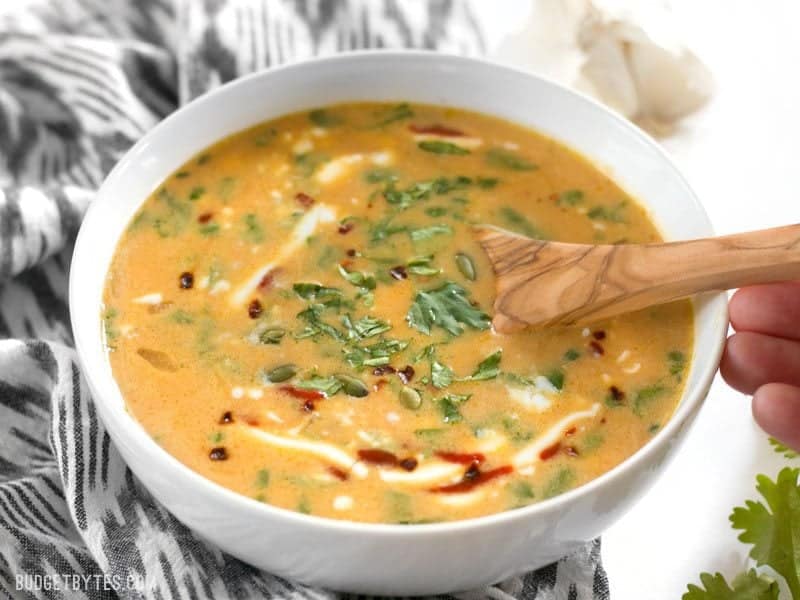 White bowl full of Spicy Coconut and Pumpkin Soup with spoon