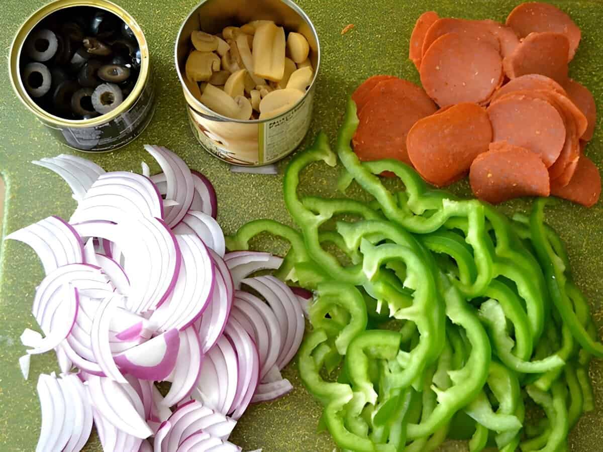 Sliced green bell pepper, sliced red onion, pepperoni, canned mushrooms and canned olives.