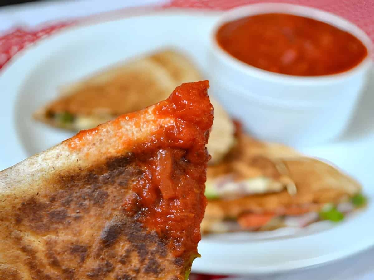 A pizzadilla dipped in marinara sauce.