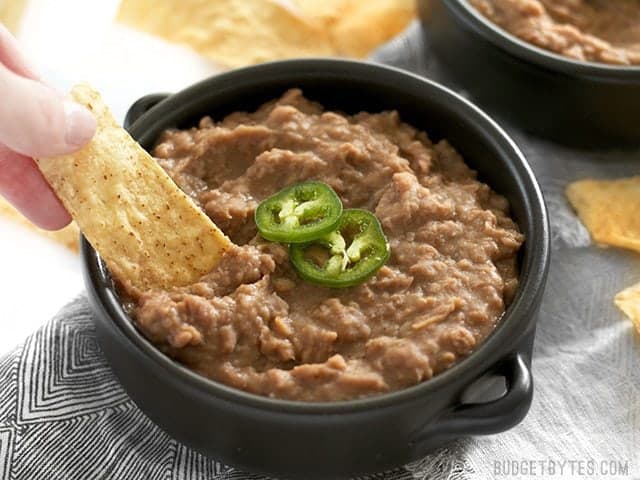 Use your slow cooker to make these incredibly flavorful (not) refried beans with next to no effort. They're versatile, delicious, and freezer friendly. Budgetbytes.com Chips being dipped into slow cooker (not) Refried Beans