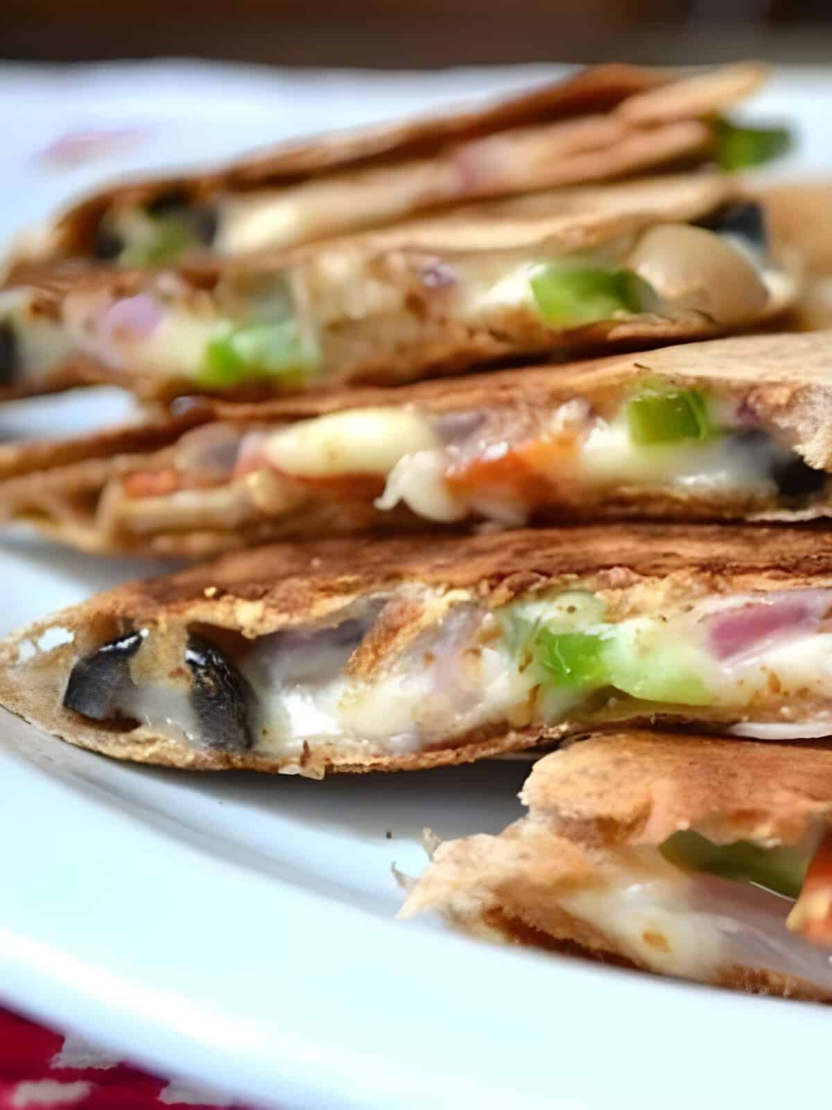 All the cheesy toppings of a pizza stuffed into a fast, easy, and crispy quesadilla, these Pizzadillas are a fast an easy alternative to traditional pizza. Budgetbytes.com Side view of a sliced pizzadilla on a plate.
