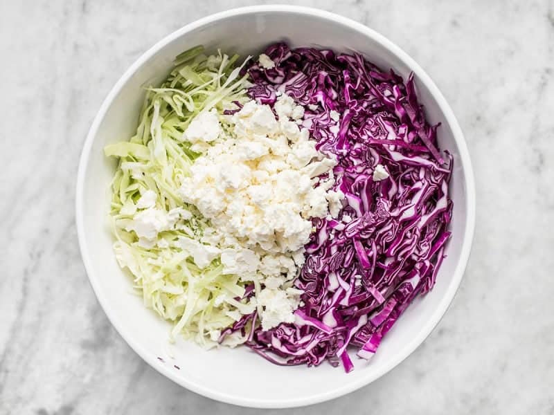 Shredded cabbage and Feta added to bowl