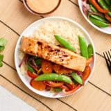 Overhead view of teriyaki salmon on a plate with stir fried vegetables and rice.