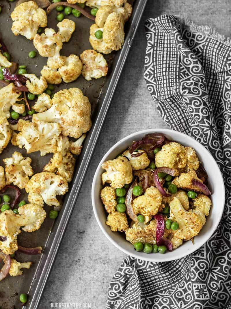 Curry Roasted Cauliflower is an easy way to turn boring cauliflower into a vibrantly spiced side dish with just a few ingredients. Budgetbytes.com A bowl of Curry Roasted Cauliflower next to the roasting sheet pan.