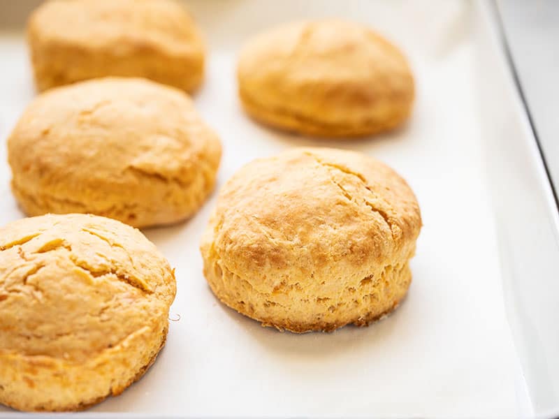 Sweet Potato Biscuits are a unique and subtly sweet twist on a classic, the perfect fall touch for your weekend brunch or Thanksgiving dinner! BudgetBytes.com Golden brown sweet potato biscuits on the baking sheet, seen from the side.