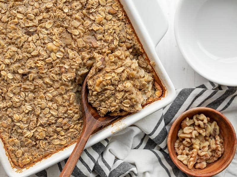 The rich and sweet flavor of banana bread infused into a healthy baked oatmeal. This Banana Bread Baked Oatmeal is perfect for breakfast meal prep! Budgetbytes.com A wooden spoon scooping baked oatmeal out of the side of the casserole dish