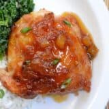 Close-up of teriyaki chicken with pineapple, served with kale and rice on a plate.