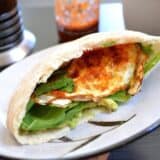 Avocado and egg pita sandwich on a plate.