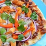Close-up of Thai chicken pizza topped with herbs.