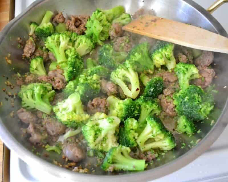 Broccoli added to the skillet with the sausage.