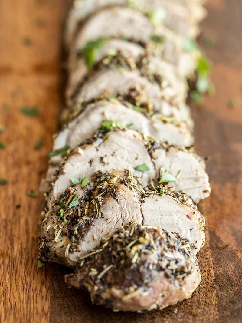 Herb Roasted Pork Tenderloin is flavorful, simple, and elegant main dish that works just as well for a weeknight dinner as it is for special dinner guests. BudgetBytes.com Front view of sliced Herb Roasted Pork Tenderloin on a cutting board