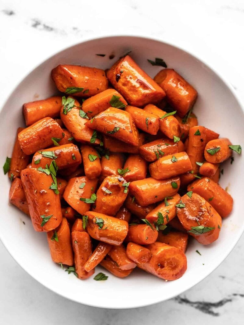 Honey Balsamic Glazed Carrots are a simple but delicious side dish that is easy enough for busy weeknights, but fancy enough for company! Budgetbytes.com A bowl of honey balsamic glazed carrots garnished with parsley