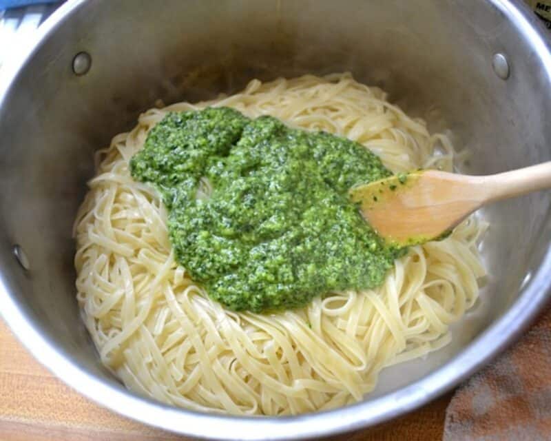 Pesto over cooked pasta in a pot.