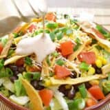 Pouring taco ranch dressing into a bowl of southwest salad.
