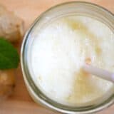 Pineapple ginger lassi in a glass with a straw.