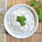 Raita served in a bowl with herbs.