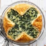 Overhead view of spinach pie in the glass pie dish on a wooden surface
