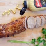 Soy dijon pork loin on a wooden cutting board.