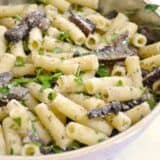 A bowl of portabella pasta garnished with herbs.