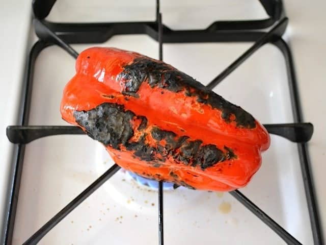 red bell pepper cooking on open flame on stove top