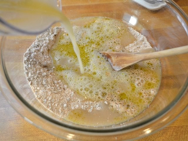 wet ingredients being poured into dry ingredients in mixing bowl