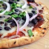 A close-up of BBQ black bean pizza with toppings.