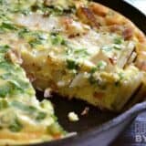 A skillet of ham and potato frittata with herbs.