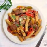 Sausage and pepper pasta served in a plate with a fork.
