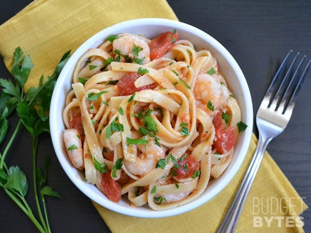 It takes less than 30 minutes to make this super flavorful and filling Spicy Shrimp Tomato Pasta. Dinner made FAST! BudgetBytes.com bowl Top view of a bowl of spicy shrimp tomato pasta with fork on the side